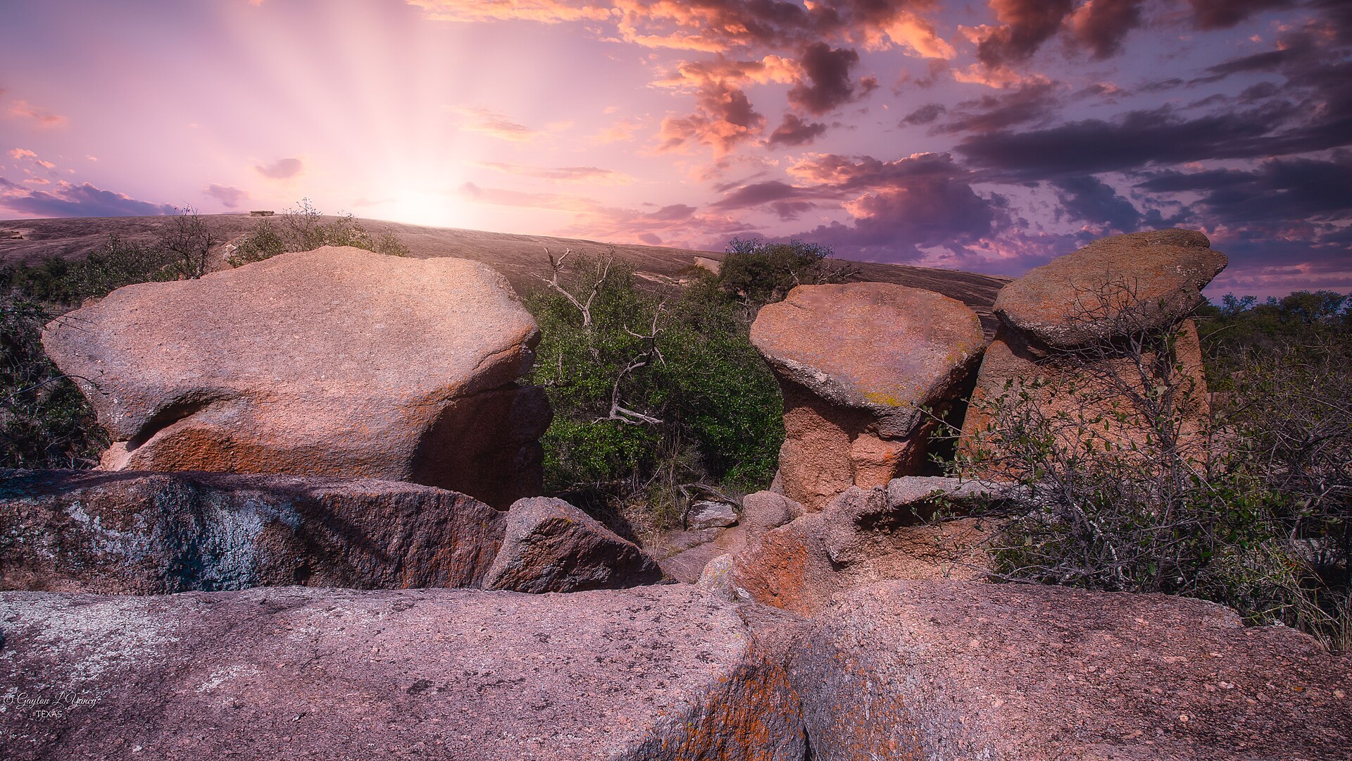 Sunset rays over the granite boulders of Enchanted Rock