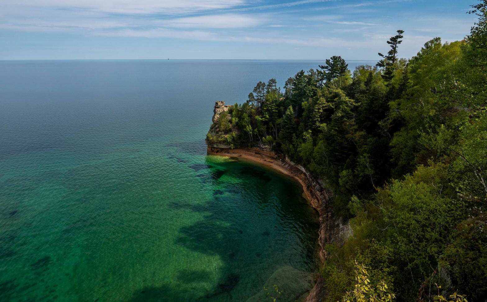 A forested headland over green Superior